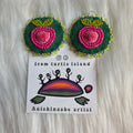 Pair of green and pink beaded  and caribou tufted earrings on a card with 'from turtle island' branding.