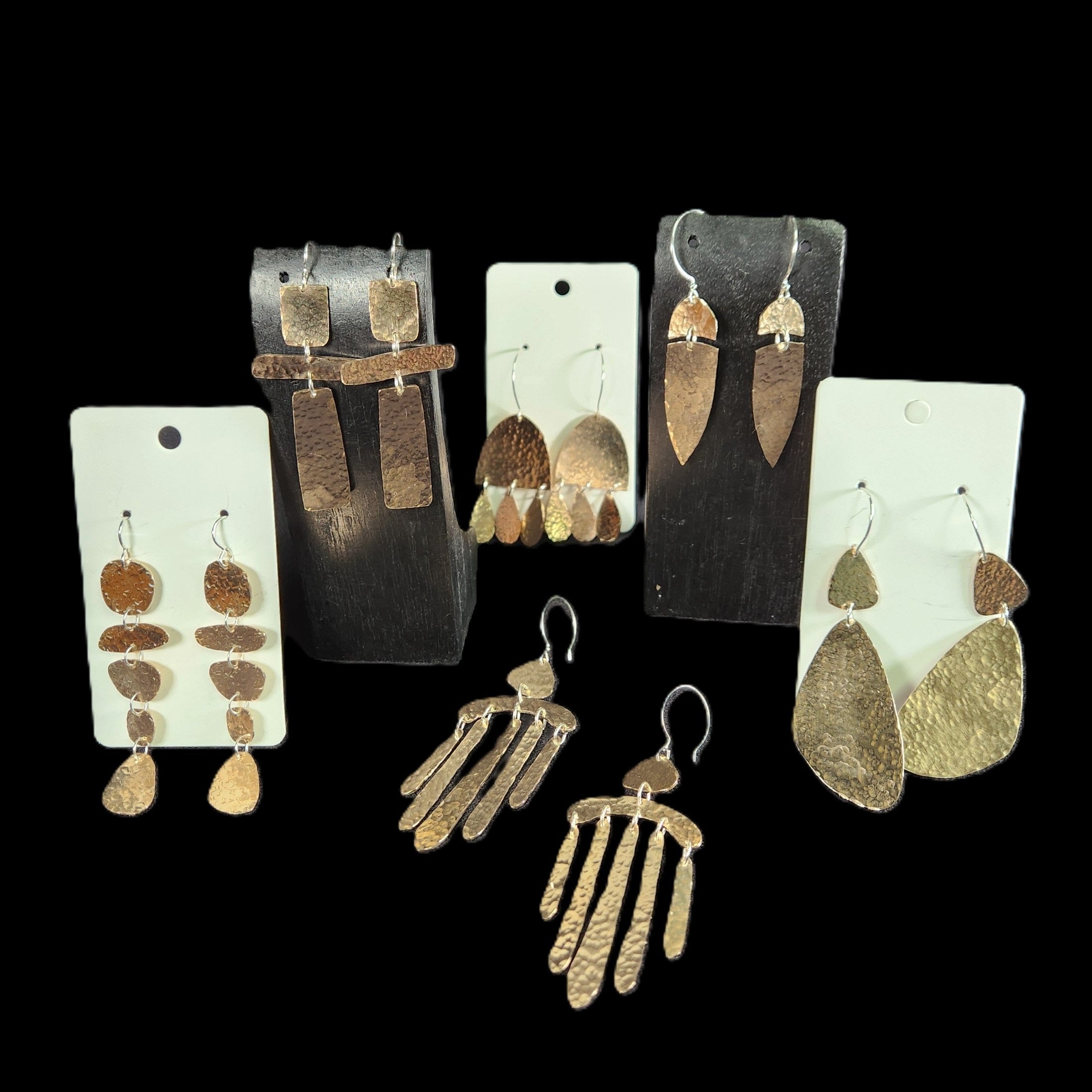 Collection of bronze earrings on display against a black background