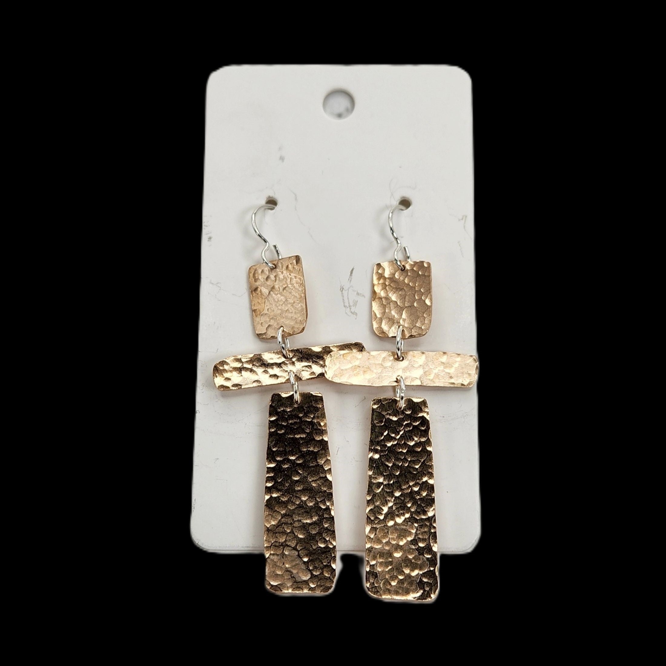 Pair of bronze earrings on a white card with a black background